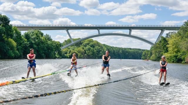 4 personnes font du ski nautique sur la Mayenne, tractées par le même bateau. En arrière plan on voit le nouveau viaduc de Château-Gontier