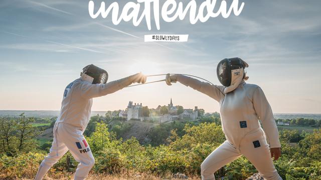 Deux escrimeurs combattent en pleine nature sur un point de vue. Au fond on voit la cité médiévale de Sainte-Suzanne